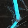 close-up of one joint of A Roar, A Boar, y Alice, a 22-foot-long sky-blue LED light sculpture by Lumencrafter, hung in the drive shed at Sourceworks Ceramics Studio for the 2018 Grey County Autumn Leaves Studio Tour. LED lights run through jointed acrylic tubes wrapped with strips of steel mesh and polycarbonate, glowing sky-blue against a dark stamped tin ceiling.. stunning; completely original.