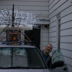 A big smile from sculptor Reid Dennison, Lumencrafter artiste extraordinaire, as he starts the journey to L.E. Shore Library, Thornbury for the the Grey Highlands Artists Collective 2017 exhibition, Sacred Spaces: Altars by Artists. Mounted on top of our old Subaru, Matrix of Beauty, original freestanding LED light sculpture. A cedar tree skeleton hung with four square light towers and overlaid with a grid of narrow polycarbonate strips.