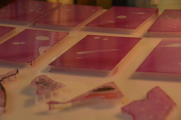 six inch by four inch panels, destined to become original LED Table Light sculptures, laid out for painting on the artist's workbench, pretty pink with cosmic splashes