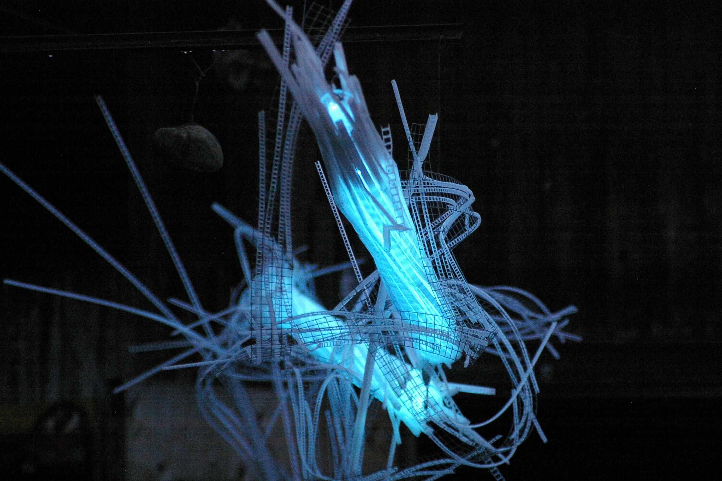A Roar, A Boar y Alice, a 22-foot-long LED light sculpture glowing blue in the dark at the 2016 Local Colour Art Garden, Flesherton, photo taken head-on so that the three joints are foreshortened..  LED lights run through three acrylic tubes joined with heavy gauge wire, wrapped with strips of steel mesh and polycarbonate.  stunning; completely original.