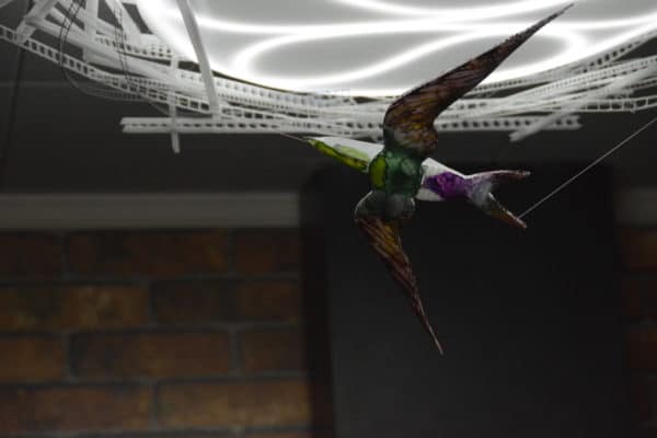Violet-green Swallow, original LED ceiling light sculpture by Lumencrafter. Close-up of hand-painted bird hanging below a 3-foot diameter diffusion plate, thin polycarbonate strips wound round create bird nest illusion.
