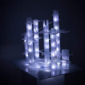 This Years' Model, a.k.a If You Lived Here, You'd be Home by Now, free-standing soft white original handmade Lumencrafter LED light sculpture, square columns of different heights connected by swirls of laddered polycarbonate twinwall strips, glowing blue-white at Arcadia Art Gallery, Toronto, 2014.