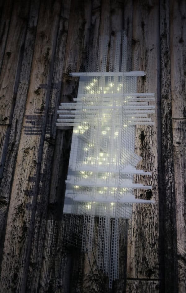 Solar Thing, unique solar-powered hand-made pale green four-foot long LED light sculpture by Lumencrafter mounted on the barn at Flesherton's Local Colour's 2020 Art Garden.