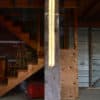 A one-inch wide strip of gold runs down the centre of a slender four-foot-long structure of polycarbonate struts and spars shot through with sparkling soft-white light.   LED light sculpture mounted on rough-hewn wooden post.