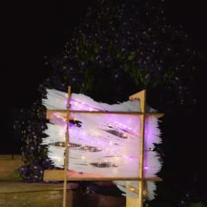 original LED light sculpture, violet-pink and white light, free-standing, slightly more than 2 feet square, glows in the garden by a cascade of deep purple clematis