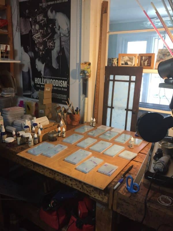 Several hand-painted light blue panels ready for assembly into free-standing LED table light by Lumencrafter.  Light yet sturdy, 6 inches high by four inch square base. Hand-painted plates of polycarbonate enclose dew drop LEDs wrapped around an inner polycarbonate core.  Indoor/outdoor. Suitable for evening al fresco dining or bedside mood lighting. Cordless; 3 AA batteries included.