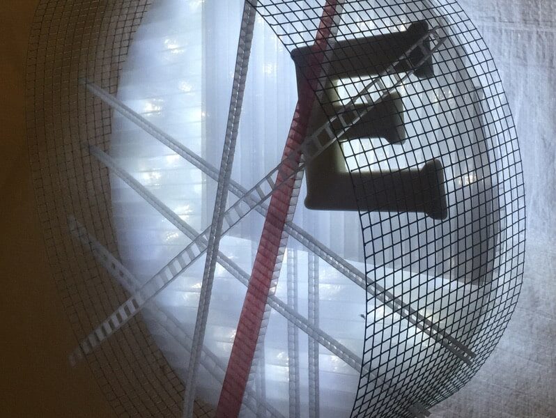 Runnin' On, original circular LED wall sconce light sculpture by Lumencrafter: A cool white LED rope light shines through a diffusion circle with large  ceramic E and painted red pointer; polycarbonate strips poke through surrounding steel mesh cylinder.  Sculpture shown at 2018 Grey County Autumn Leaves Studio Tour.