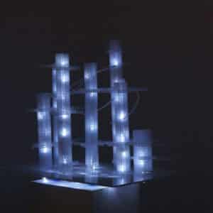 This Years' Model, a.k.a. If You Lived Here, You'd be Home by Now, free-standing original handmade Lumencrafter LED light sculpture, square columns of different heights connected by swirls of laddered polycarbonate twinwall strips, glowing blue-white at Arcadia Art Gallery, Toronto, 2014.