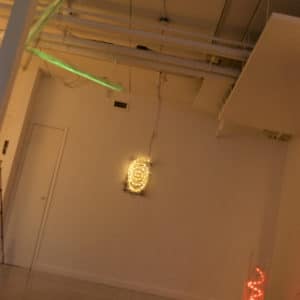 Three original handmade Lumencrafter LED light sculptures, green zigzag on ceiling, red spiral on floor, and soft white wall sconce spiral at Arcadia Art Gallery, Toronto, 2014.